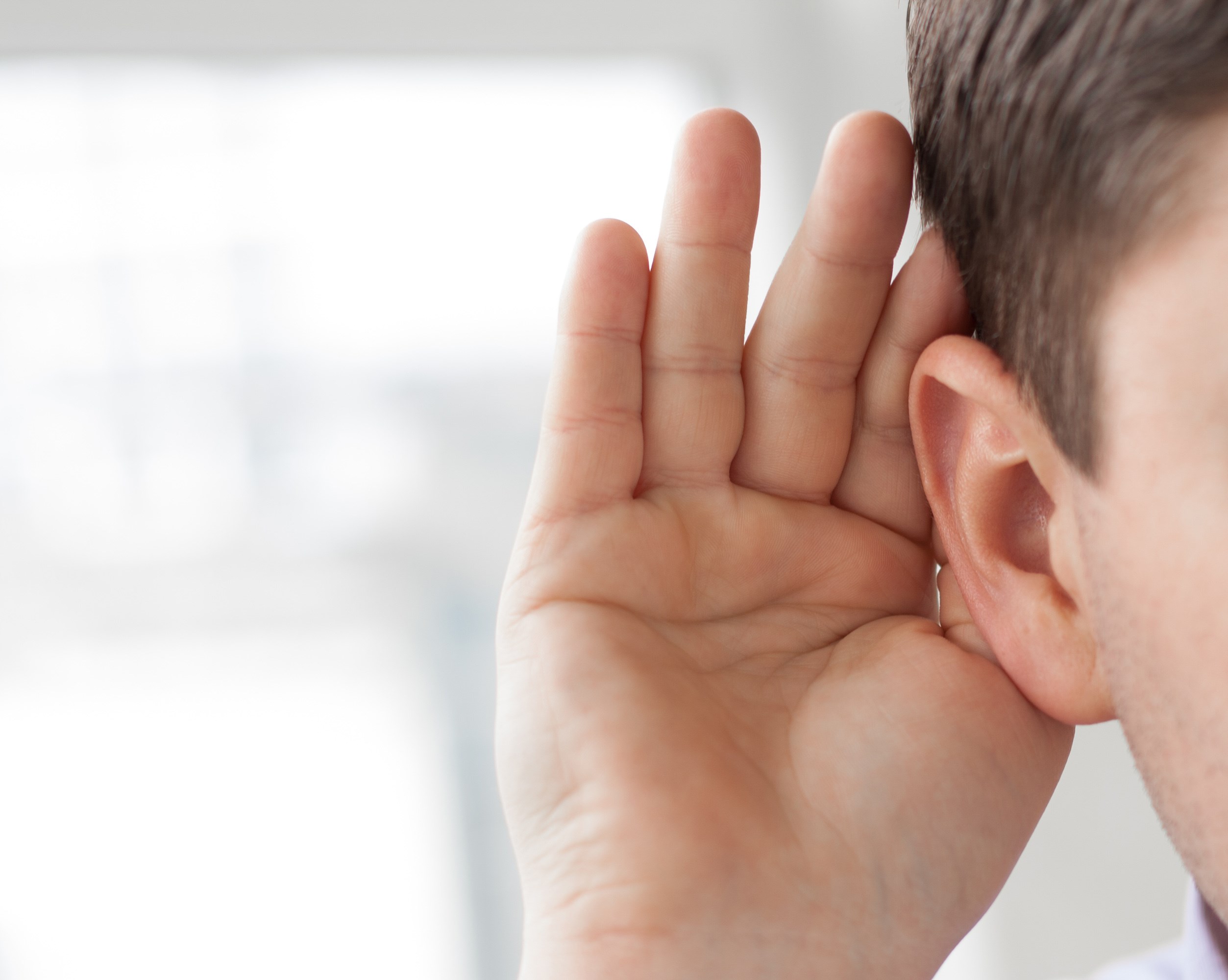 Nærbillede af øre. Personen holder sin hånd bag øret for at lytte bedre.